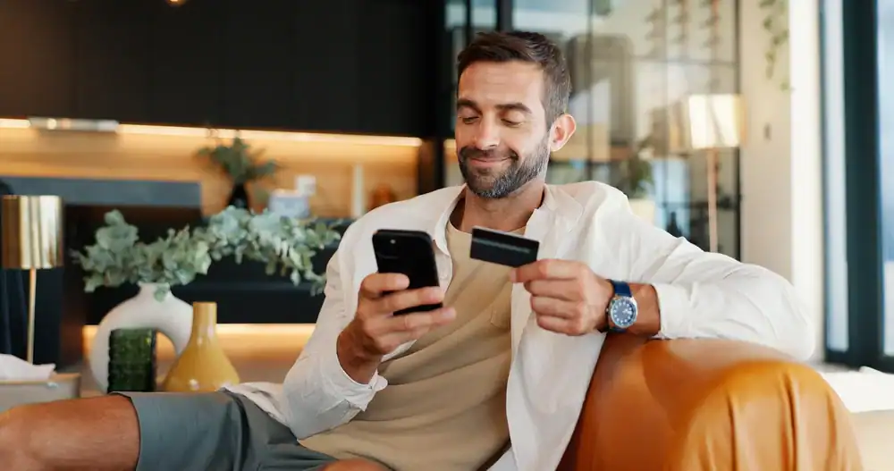 Alt="Man using smartphone for secure digital payment with credit card in modern cafe".