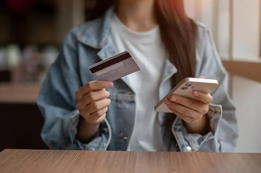 Image of a woman using her smartphone and credit card for secure payment.