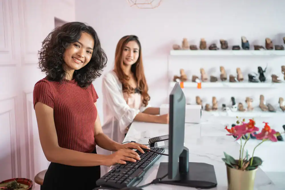 Alternative text: Two women shopping for shoes in a trendy boutique store with display shelves.