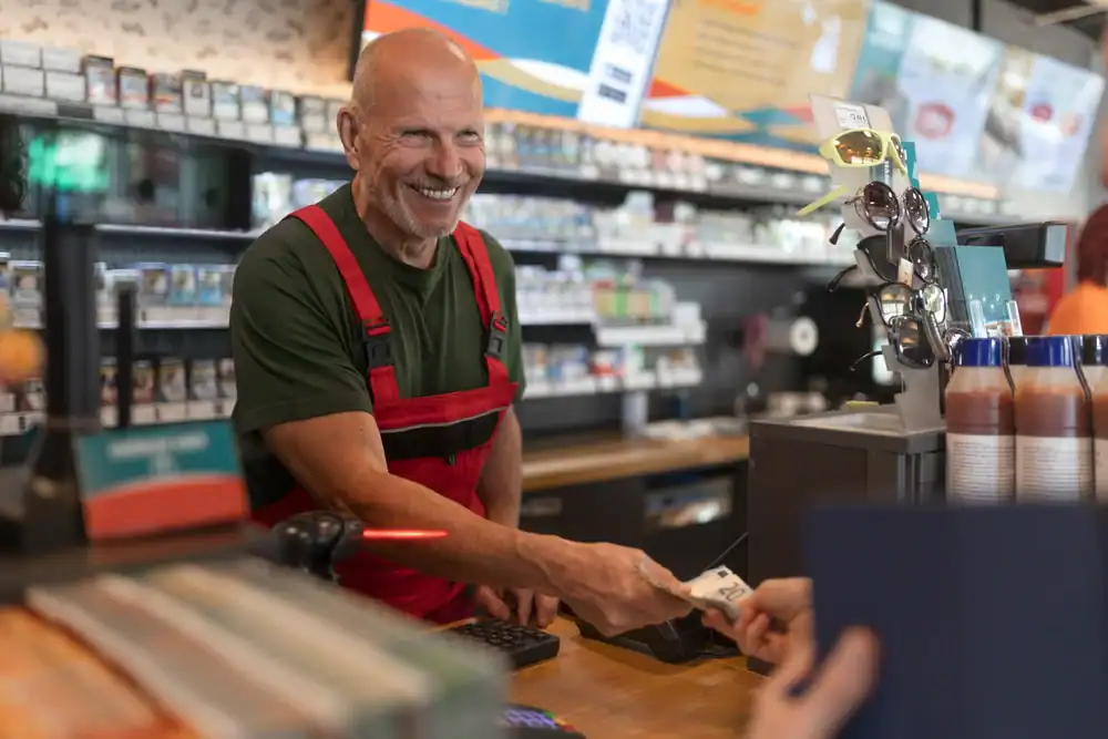 Friendly pharmacy staff assisting customers at the counter in a retail store.
